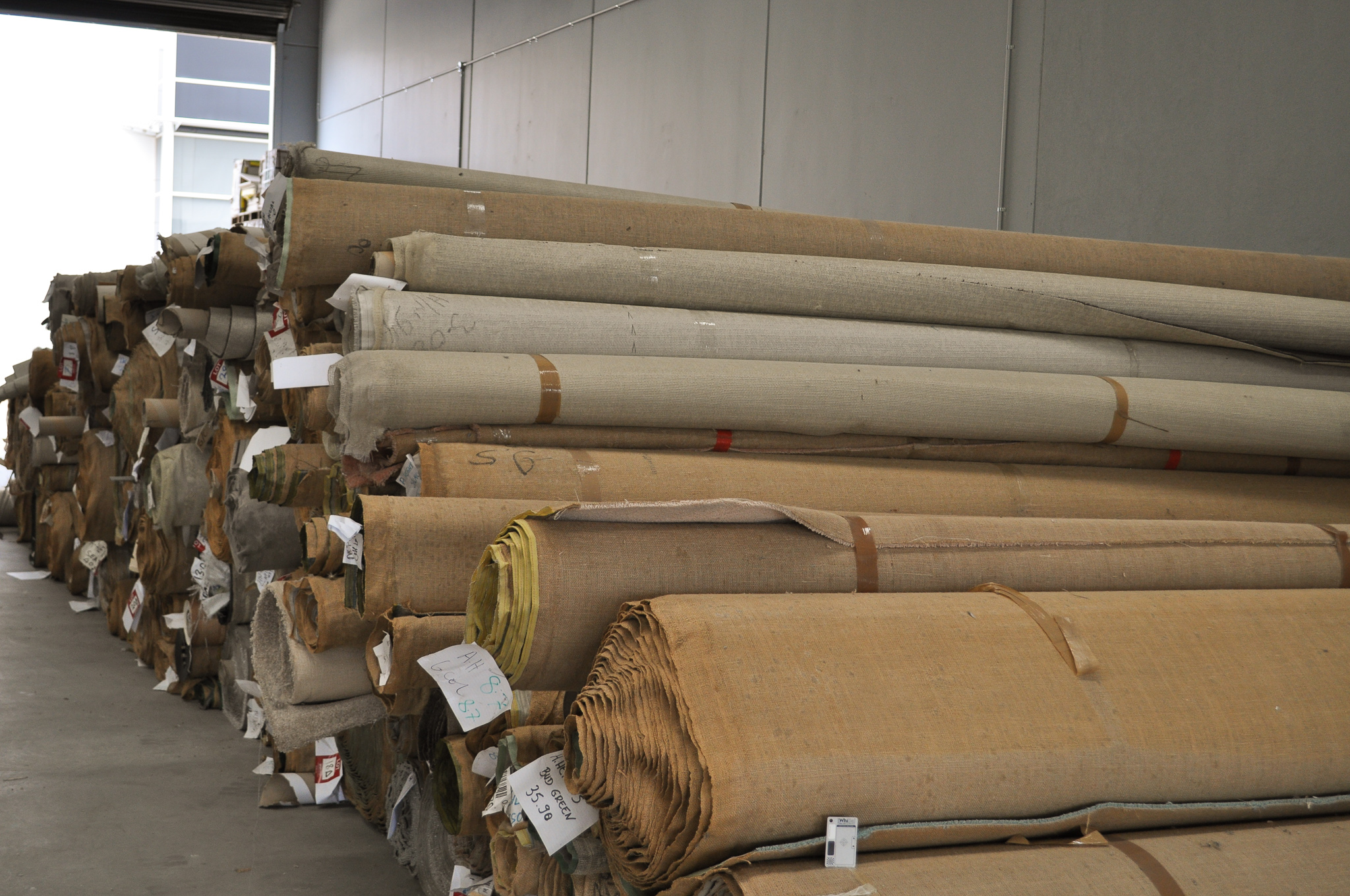 rolls of carpet in the warehouse of Concord Floors, they being carpet stock of Concord Floors.