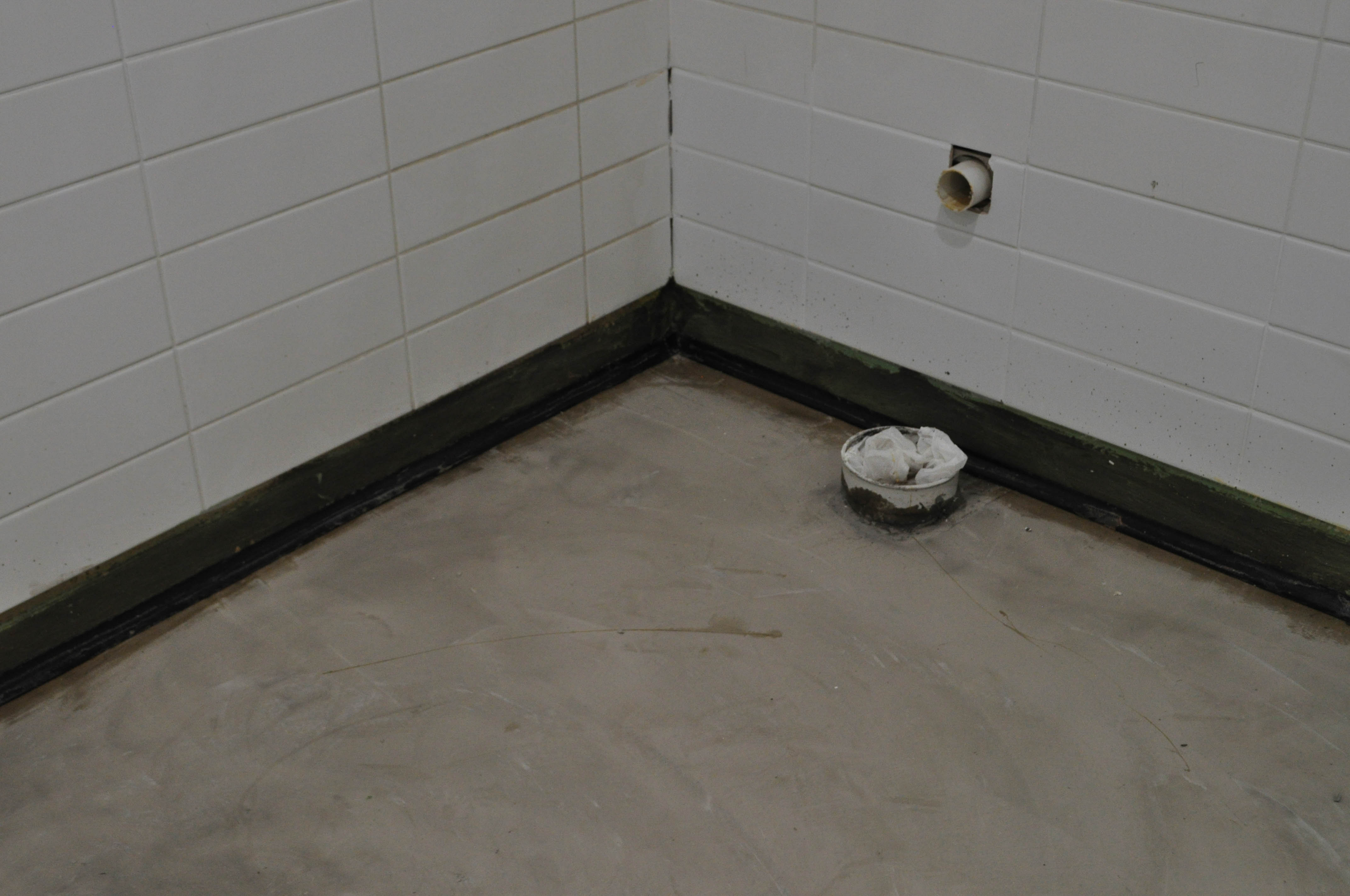 showing the floor of a corner of the toilet in which the floor has been levelled with a levelling compound and cove fillet installed at
 the edges of the room.
