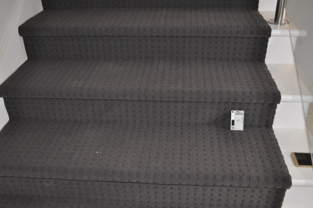 showing a staircase with charcoal colored carpet installed on it.